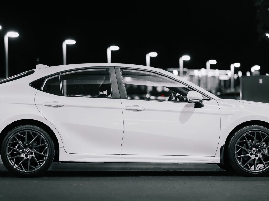 Service-2-min Side view of a stylish white sedan at night, highlighting modern design and urban ambiance.